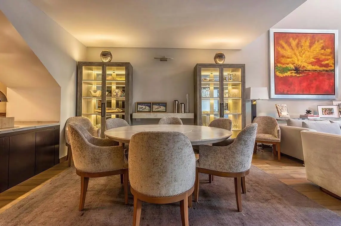Comedor residencial con mesa y sillas junto a grandes ventanales